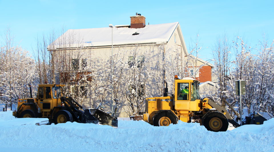 Två traktorer röjer snö i ett villakvarter