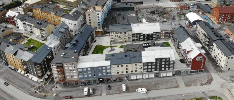 Fotot är taget från drönare och visar hus i en stadskärna på sommaren.