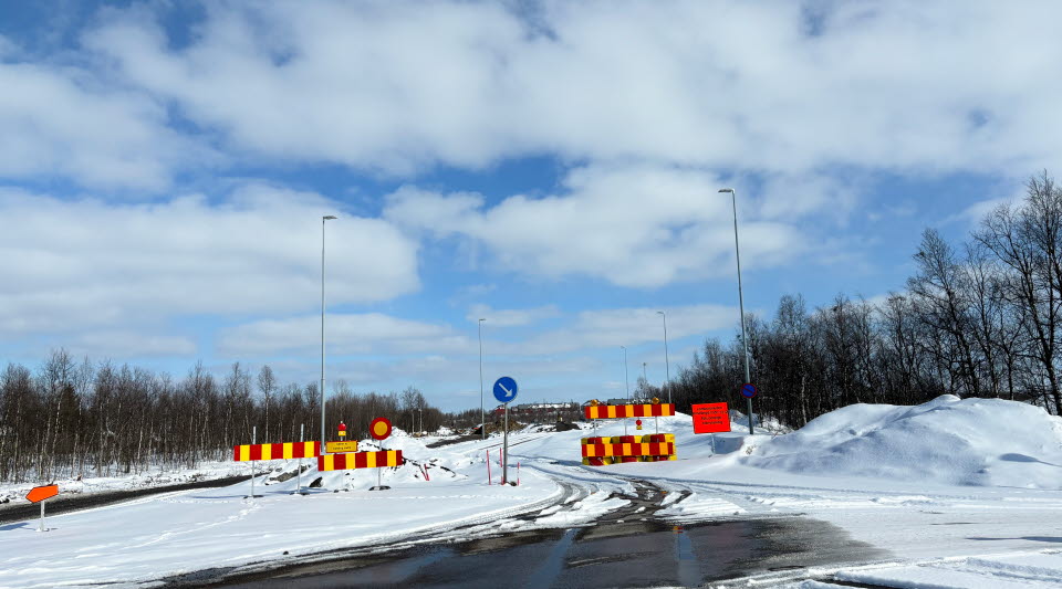 Fotot visar en avstängd väg med vägbommar och snö på sidorna. 