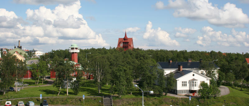 Sommarvy över gamla brandstationen och sjukstugan med Kiruna kyrka i bakgrunden. 