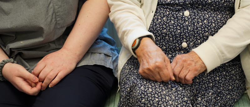 Pensionär sitter jämsides med en yngre person