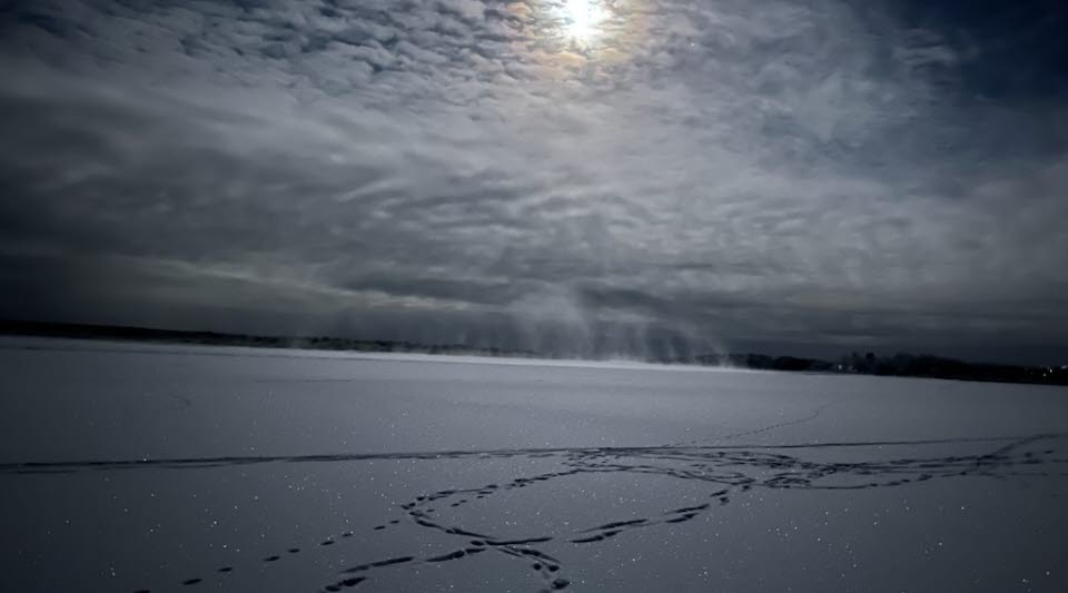 En vinterbild med sol bakom en molnig himmel