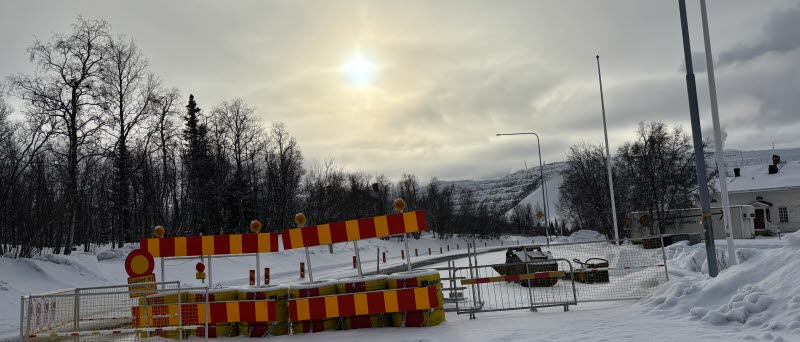 Fotot visar en avspärrad väg med ett vitt hus till höger. 