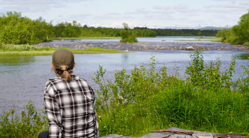 Person som blickar ut mot älven en sommardag