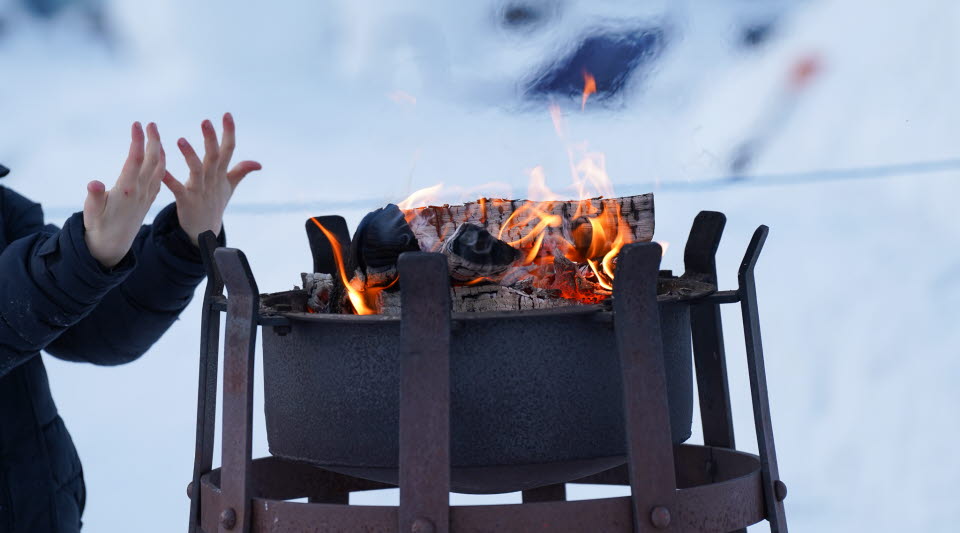 Barnhänder som värmer sig framför en uteeld