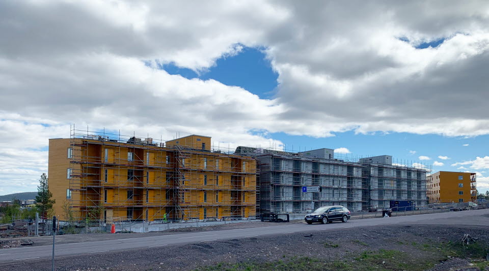 Fotot visar gula flerfamiljshus med en väg framför. 