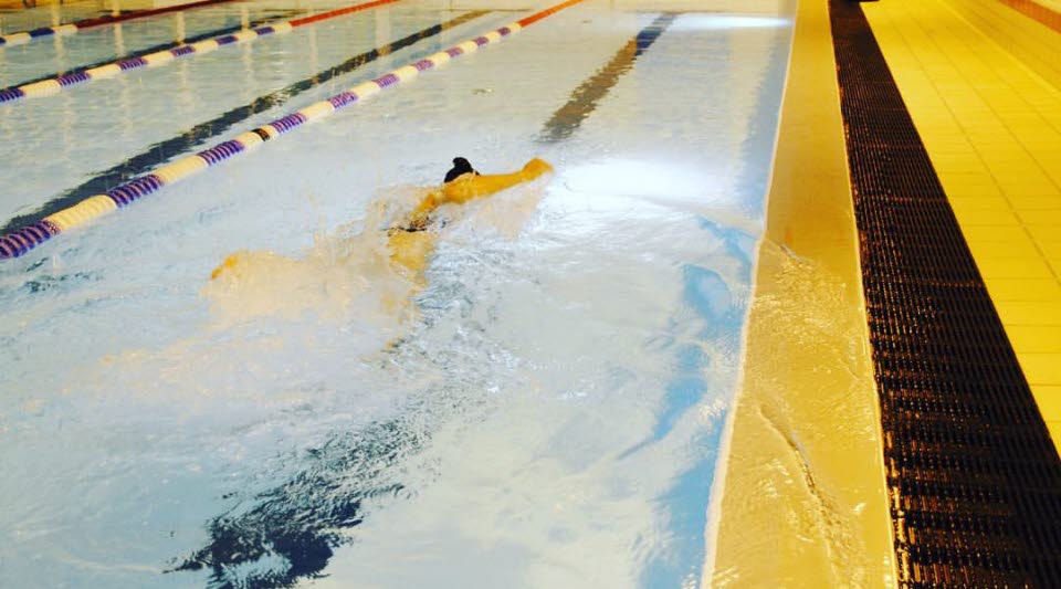 En människa som simmar i motionsbassängen.