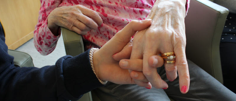 Närbild på två händer som håller i varandra.