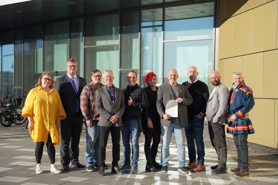 Lisa Forsberg, Stefan Sydberg, Magnus Gustafsson, Mats Taaveniku, Sten Nylén, Sanna Inga Poromaa, Niklas Sirén, Jonas Stålnacke, Krister Pounu, Per-Olof Nutti står framför Kiruna stadshus i solsken.