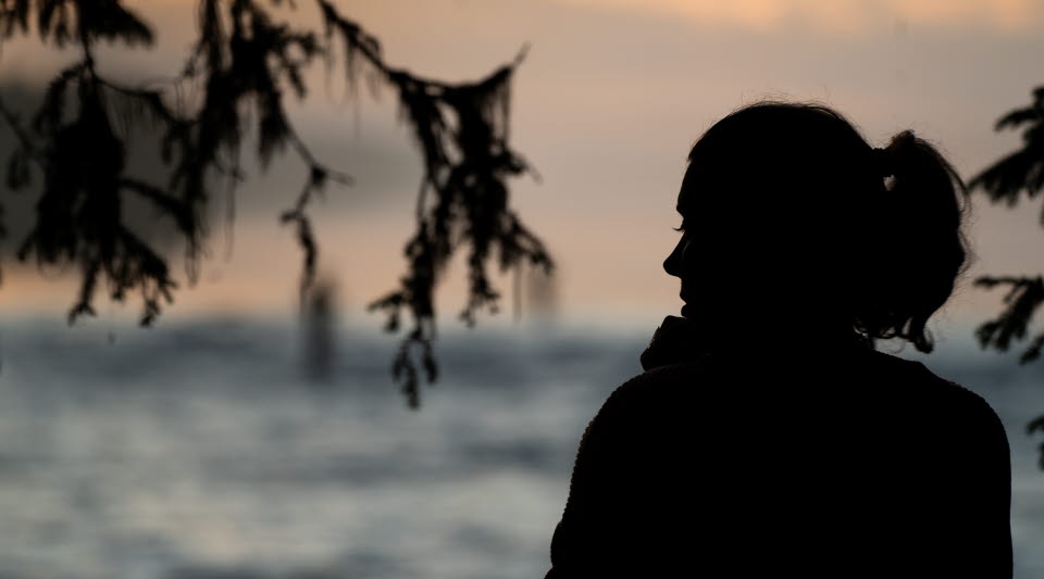 En kvinna som sitter i profil och tittar ut mot vatten