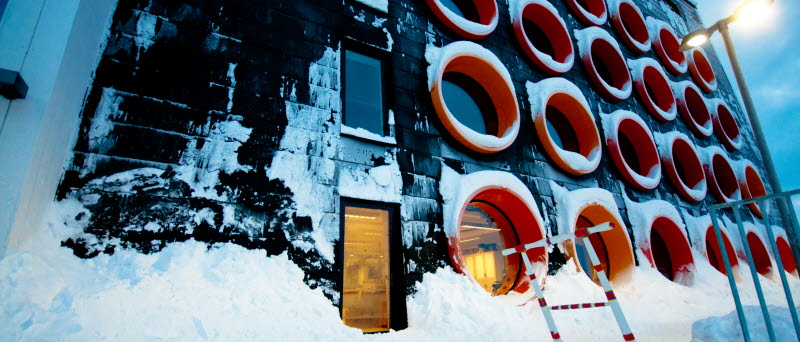 Nya Raketskolans fasad med de röda, runda fönstren i vintermiljö.