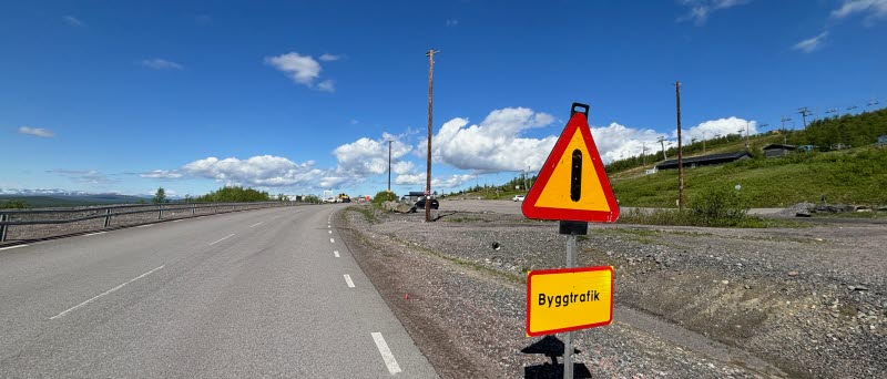 Fotot visar en skylt med texten byggtrafik och en väg  med arbetsfordon längre bort.