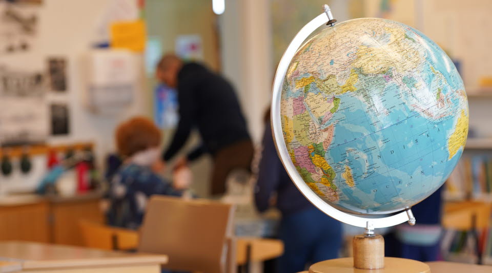 Förskolelokal med barn och pedagog som pysslar kring ett bord.