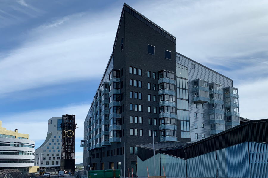 En brun och grå byggnad med Kirunas nya stadskärna i bakgrunden. 
