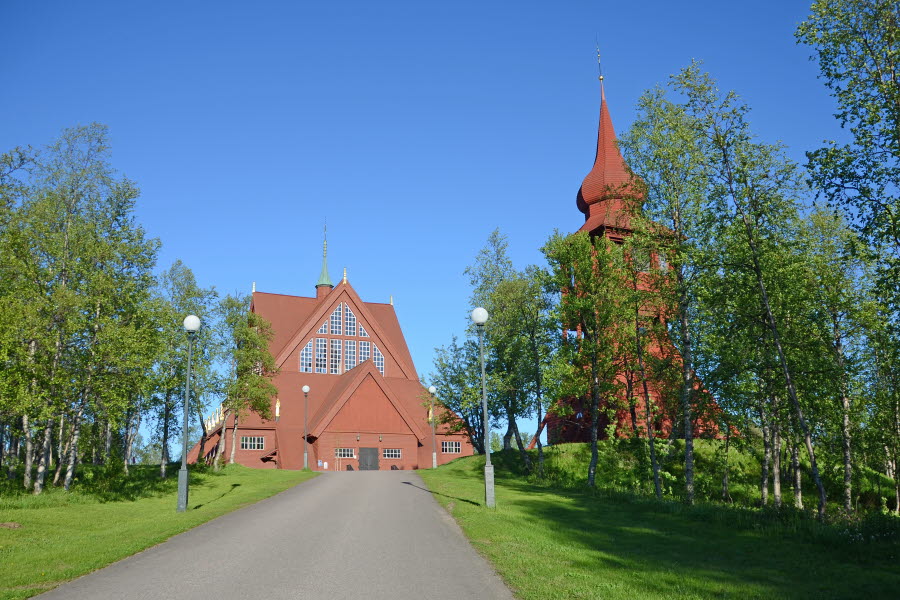 Fotot visar en kyrka och en klockstapel sommartid.