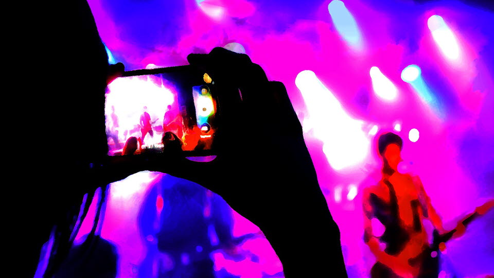Någon fotar en konsert med mobilkamera. 