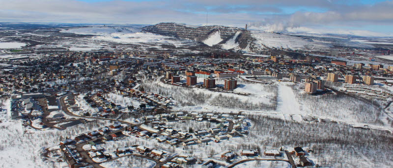 Flygfotot visar Kiruna stad på vintern med gruvan i bakgrunden.