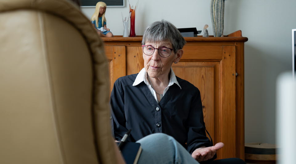 Kvinna som samtalar med en person som sitter i en fåtölj