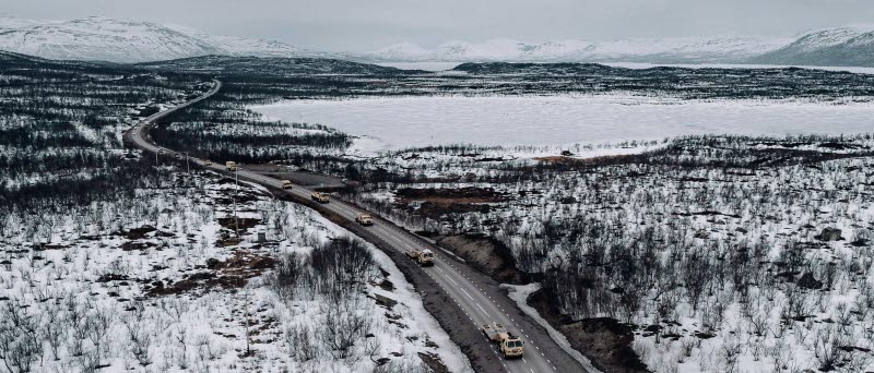 En miliärkolonn längs en vinterväg i fjällen.