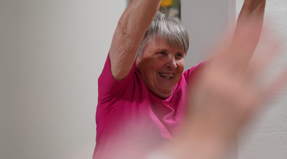 Glad pensionär som gör sittgympa