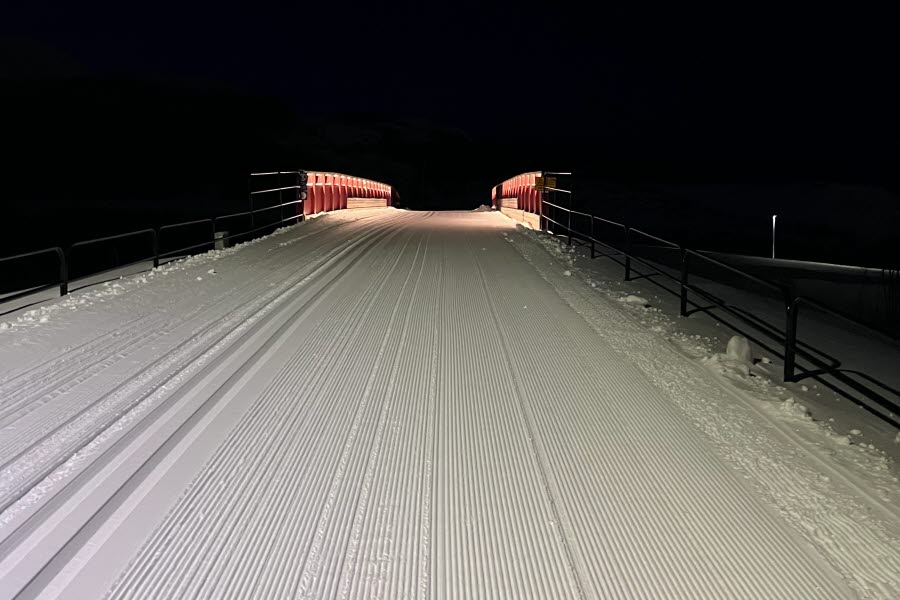 Fotot visar ett skidspår och en upplyst bro.