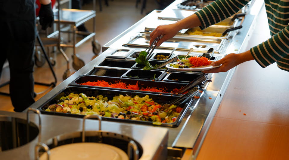 Elev tar sallad från lunchbuffén. 