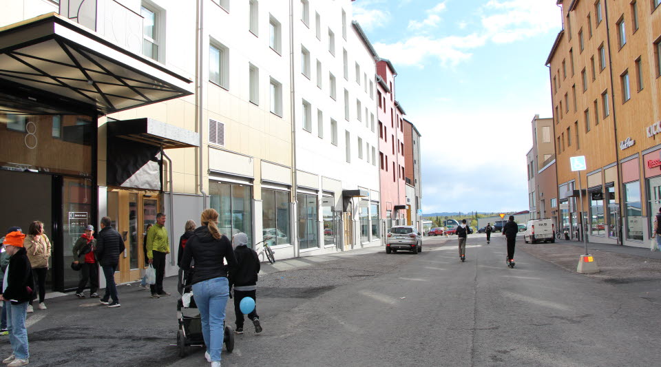 Fotot visar en affärsgata med personer som promenerar.