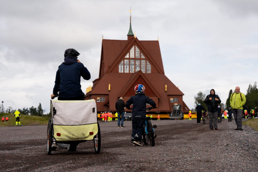 En förälder tittar tillsammans med sitt barn på flytten av Kiruna Kyrka.