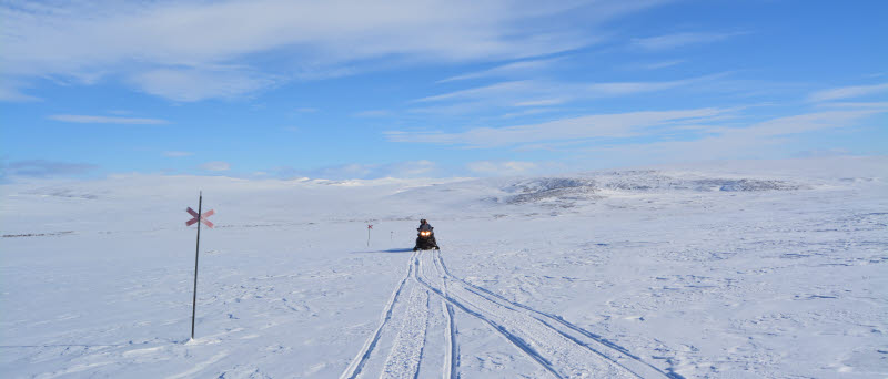 en skoter kör på en snötäckt skoterled
