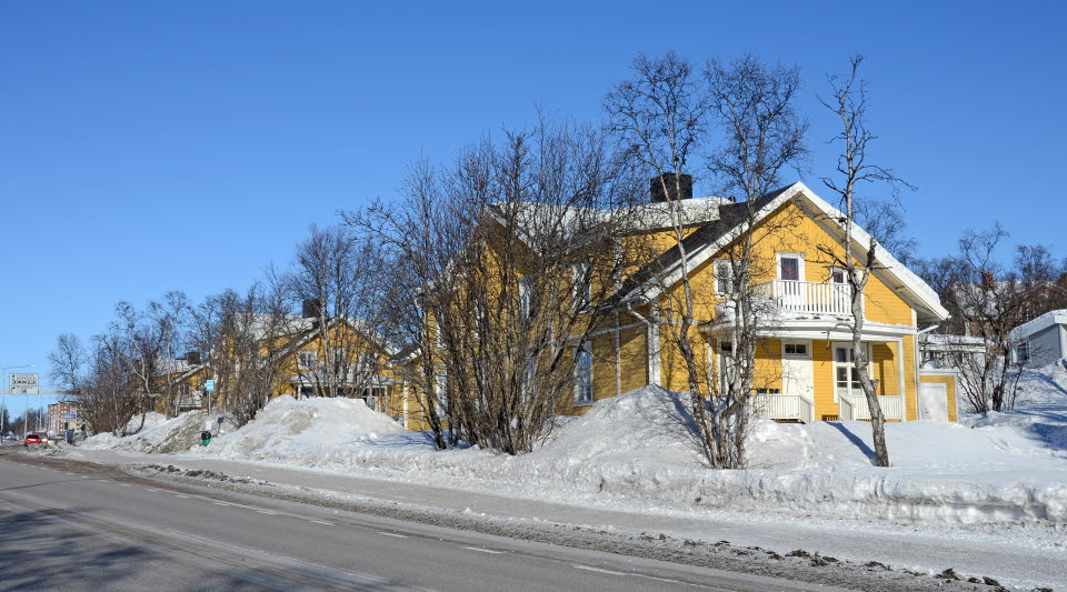 På fotot ser vi gula byggnader omgivna av snö och blå himmel.