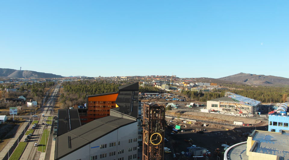 Fotot är taget uppifrån och visar en väg med byggnader framför och på sidan med en blå himmel bakom