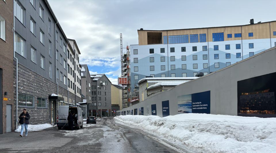 Fotot visar en gata med byggnader på båda sidor med en blå byggnad till höger. 
