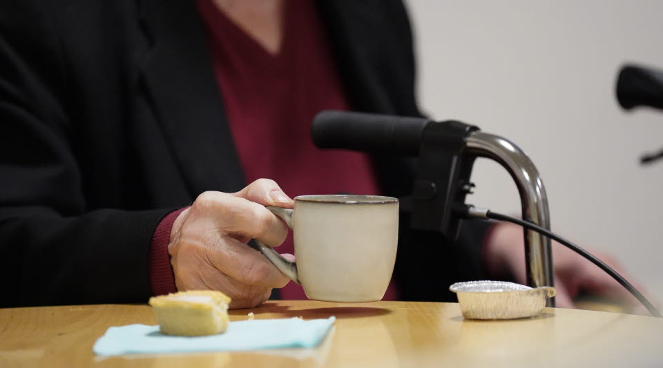 En person som håller i en kaffekopp med en mazarin på bordet