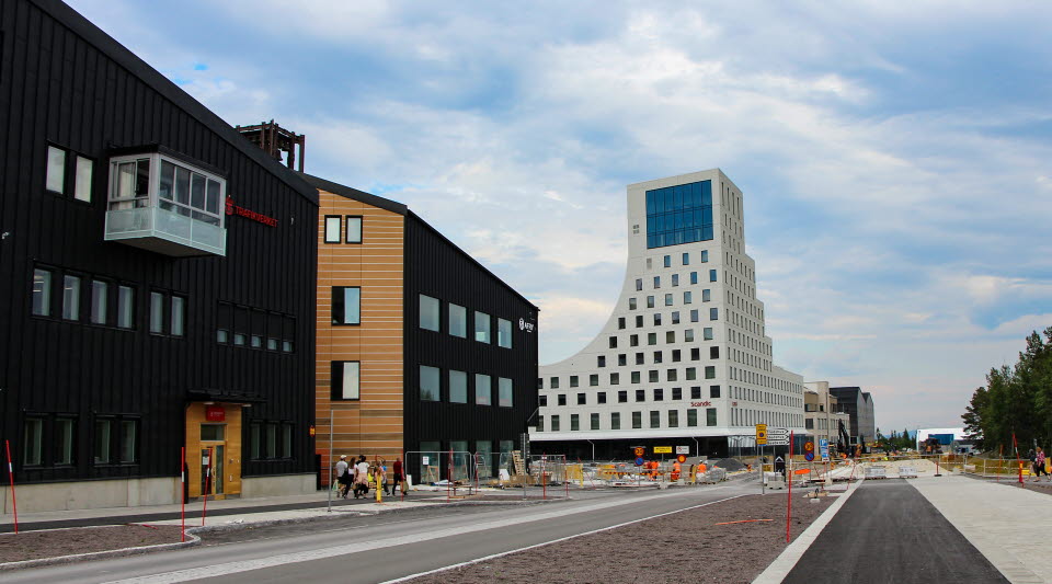 Malmvägen in till Kirunas nya stadskärna med en brun byggnad till vänster och en vit byggnad rakt fram. 