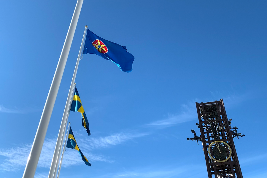 Fotot visar flaggor mot en blå himmel. 